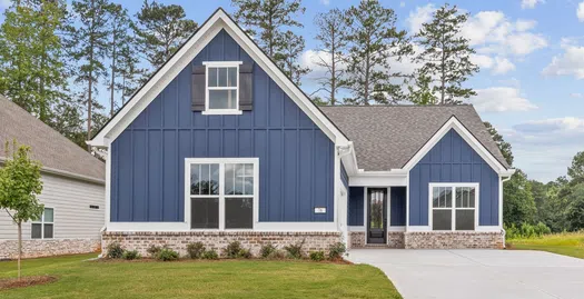 Modern blue house with white trim, large windows, well-maintained lawn, and concrete driveway on a sunny day.