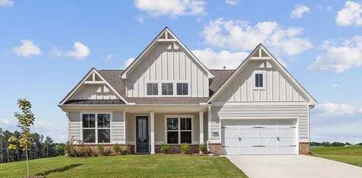 Modern white farmhouse with gable roof, two-car garage, manicured lawn, and clear blue sky background.